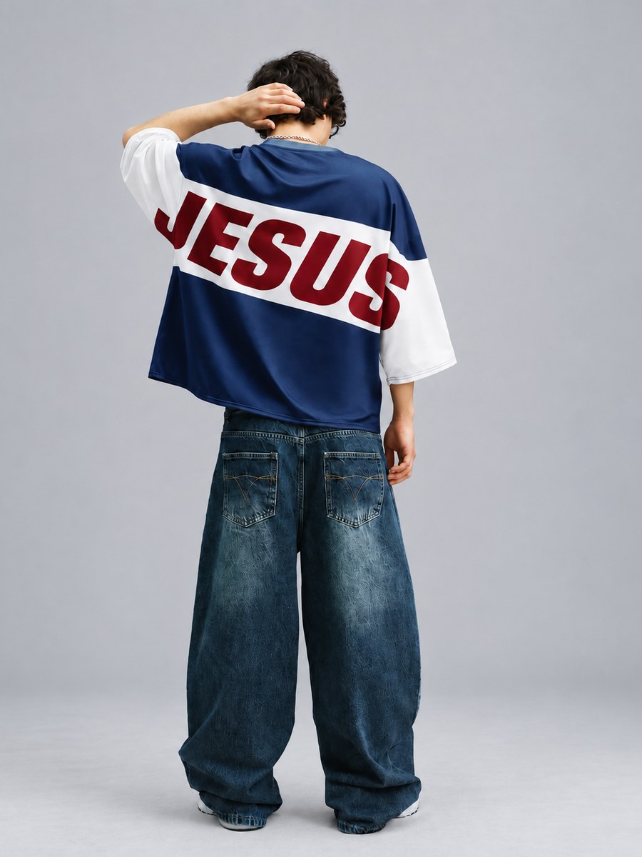 Navy and white colour-block tee with 'JESUS' in red across the back, worn with wide-leg jeans